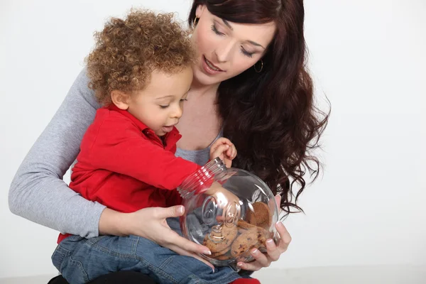 Little boy grabbing biscuit from jar — Stock Photo, Image