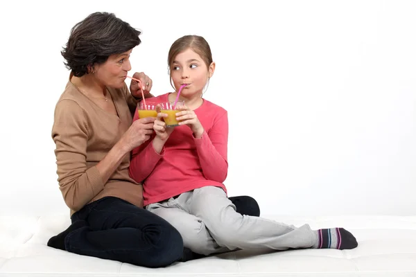 Little girl having a drink with her grandma — Stock Photo, Image