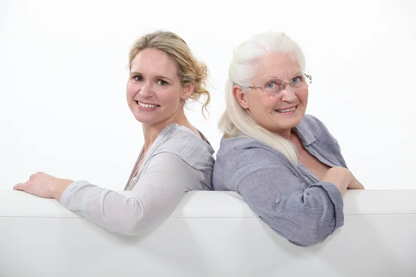 Mother and daughter sitting on white sofa — Stock Photo, Image