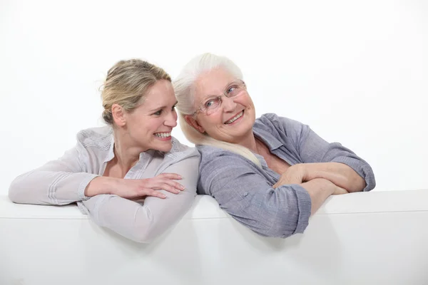Két nő, egy fehér kanapé — Stock Fotó