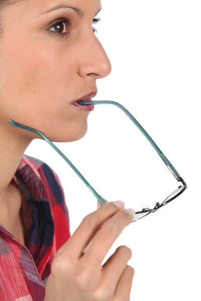 Kobieta myśli z jej okulary w jej ustach — Zdjęcie stockowe