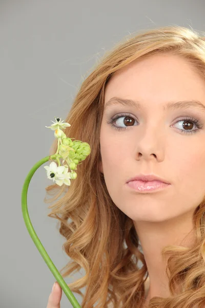 Plan studio d'une belle jeune femme maquillée tenant une fleur délicate — Photo