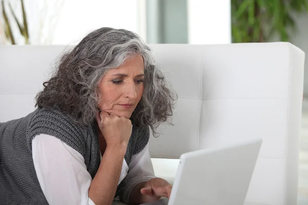 Starsza kobieta, wpisując na jej laptopie — Zdjęcie stockowe
