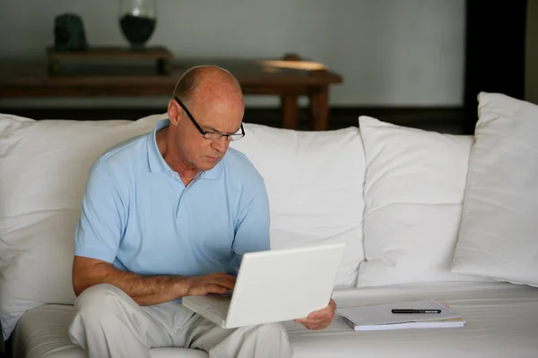 Ein älterer Mann arbeitet zu Hause an seinem Laptop — Stockfoto