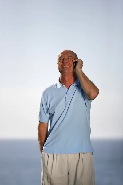 Homem sênior fazendo chamada telefônica pela costa — Fotografia de Stock