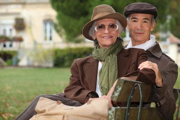 Elegantní pár sedící na lavičce v parku — Stock fotografie