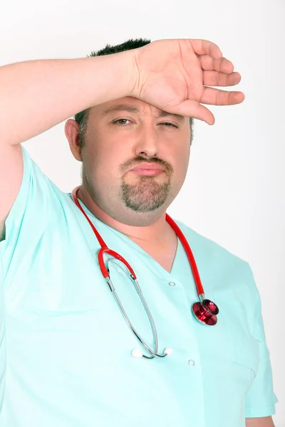 Médico sobrecarregado em fundo branco — Fotografia de Stock