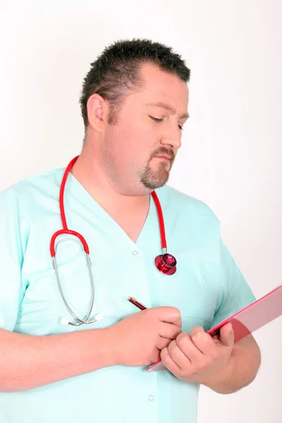 Male doctor writing on clip board — Stock Photo, Image