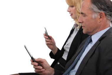 Business partner both checking e-mails on cellphone clipart