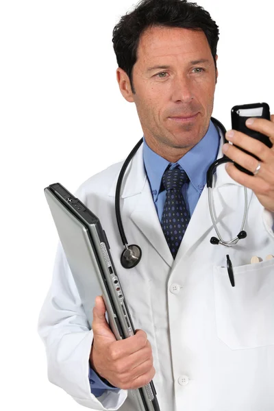 Lekarz patrząc na telefon komórkowy — Zdjęcie stockowe