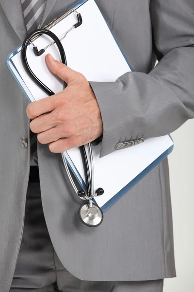 Closeup schránky a stetoskop drží muž v obleku — Stock fotografie