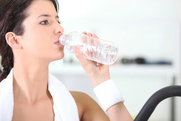 Žena pije láhev vody v tělocvičně — Stock fotografie