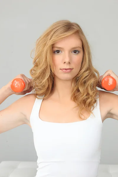 Blondes Mädchen mit orangefarbenen Gewichten — Stockfoto