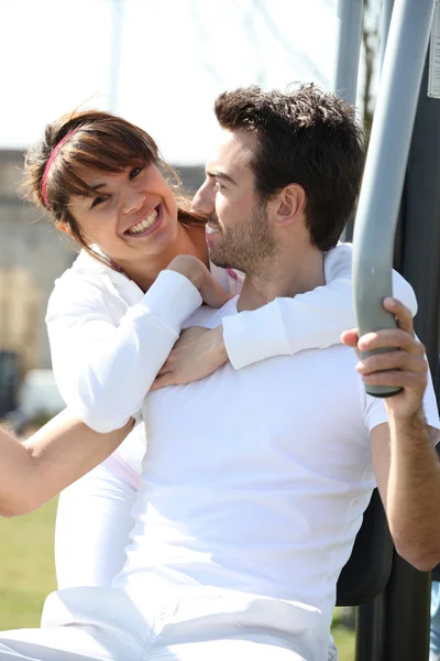Couple using outdoor gym equipment — Stock Photo, Image