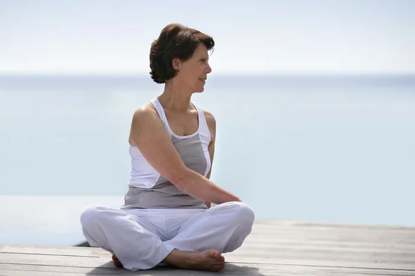 Frau praktiziert Yoga auf einem Deck — Stockfoto
