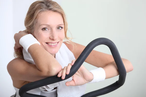 Mulher loira em bicicleta de exercício no ginásio — Fotografia de Stock