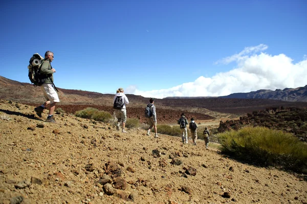 Grupo turístico caminhando em uma paisagem árida — Fotografia de Stock