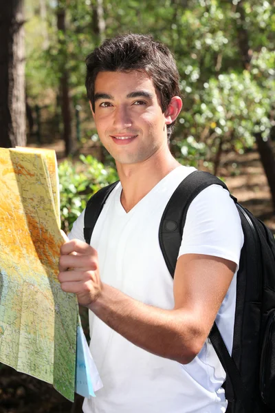 Mladý muž, čtení mapy v lese — Stock fotografie