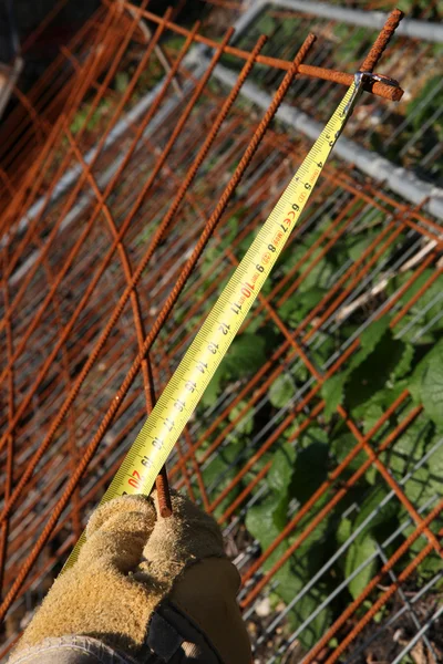 Arbetstagaren mäta rostig staket — Stockfoto