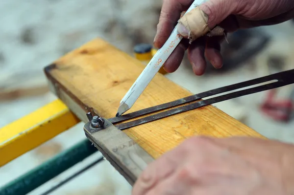 Carpintero usando set cuadrado para marcar madera — Foto de Stock