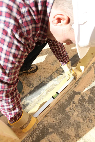 Pracownik budowlany za pomocą poziomnicy — Zdjęcie stockowe