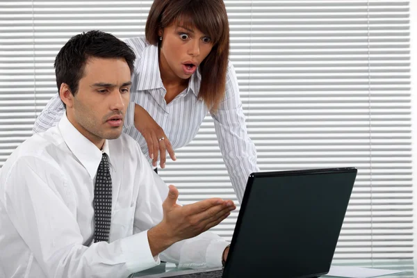 Couple d'affaires choqué devant un ordinateur portable — Photo
