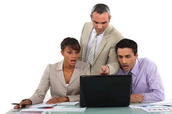 Manager und seine schockierten Mitarbeiter blicken auf einen Laptop — Stockfoto