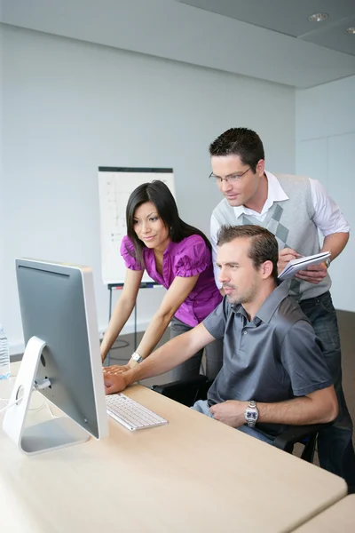 Trio dinâmico trabalhando em um computador desktop — Fotografia de Stock