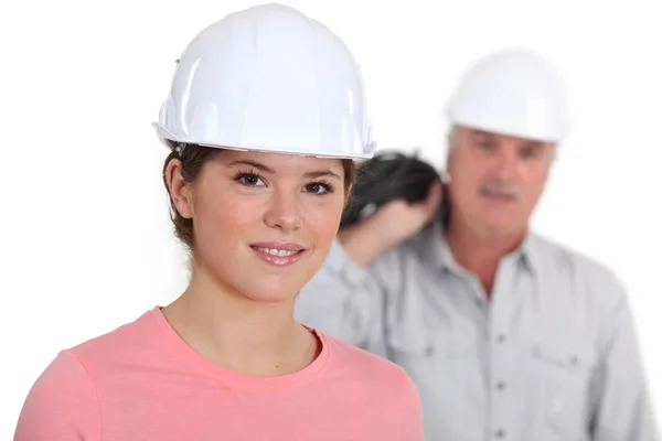 Porträt einer jungen Handwerkerin mit ihrem Chef im Hintergrund — Stockfoto