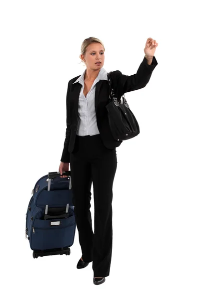 Blond businesswoman with luggage hailing taxi — Stock Photo, Image
