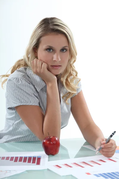Woman sat at desk working on graphs Stock Photo