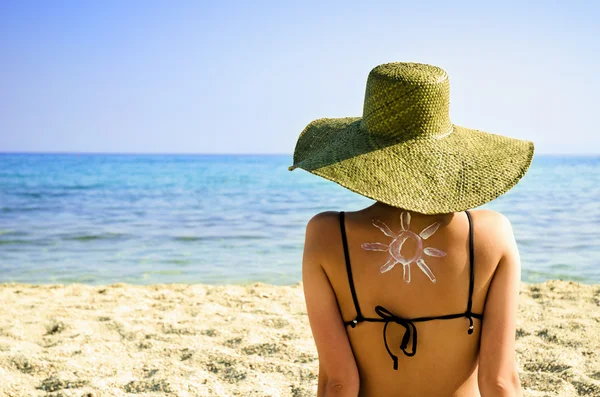 Femme sur la plage avec le symbole du soleil sur le dos — Photo