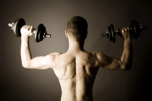 Muscle man lifting dumbbells — Stock Photo, Image