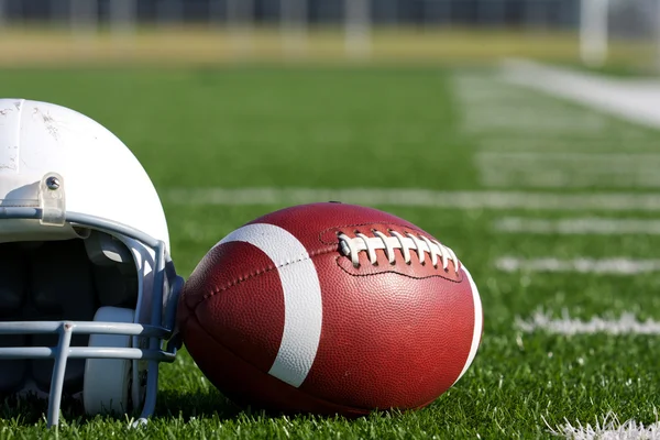 Американский футбол и шлем на поле — стоковое фото