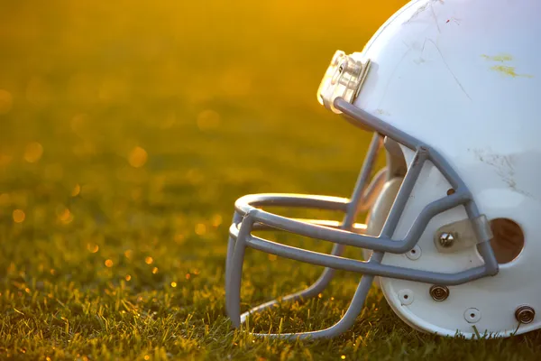 フィールドのバックライト付きのアメリカン フットボールのヘルメット — ストック写真