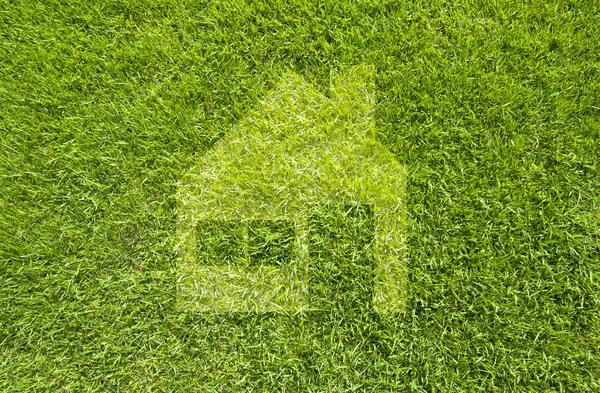 Піктограма будинку на зеленій траві, фон з текстури — стокове фото