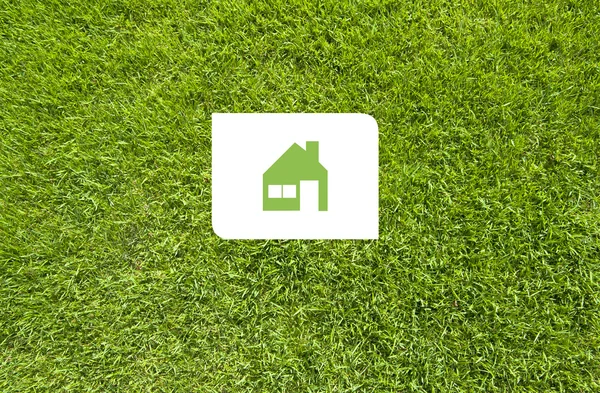 Icon home on green grass, texture background — Stock Photo, Image