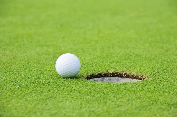 Golf ball op rand van gat — Stockfoto