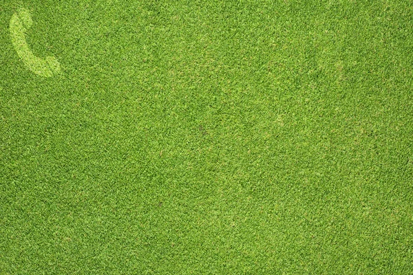 Значок телефона на зеленой текстуре травы и фоне — стоковое фото