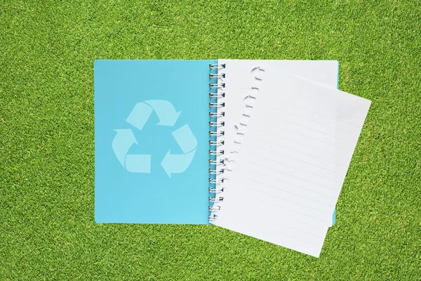 Livro com ícone de reciclagem no fundo da grama — Fotografia de Stock