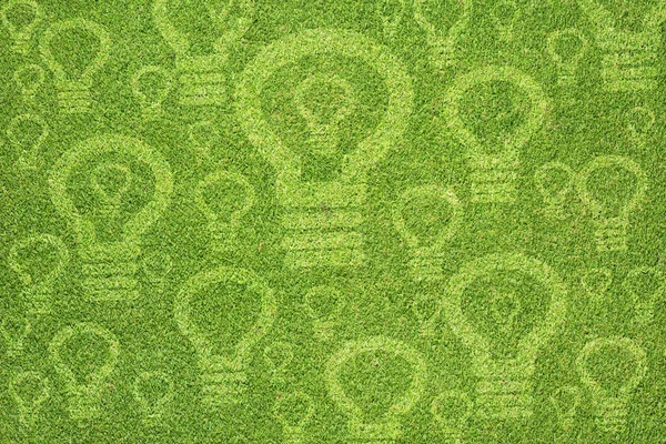 Значок лампочки на зеленой текстуре травы и фоне — стоковое фото