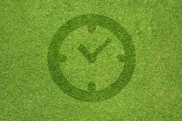 Ícone do relógio na textura de grama verde e fundo — Fotografia de Stock