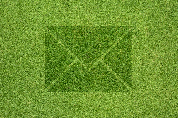 Значок почты на зеленой текстуре травы и фоне — стоковое фото