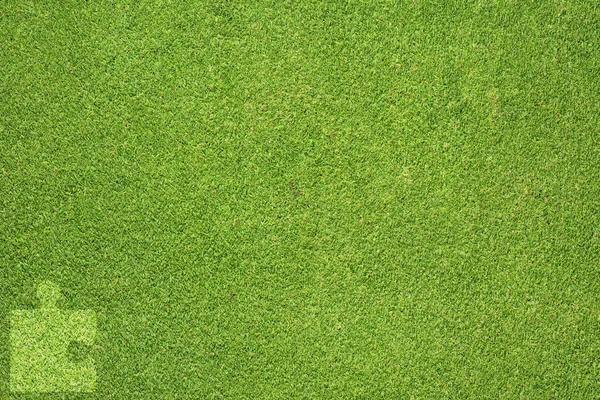จิ๊กซอว์บนพื้นผิวหญ้าสีเขียวและพื้นหลัง — ภาพถ่ายสต็อก