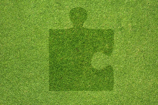 Jigsaw simgesi yeşil çim doku ve arka plan — Stok fotoğraf