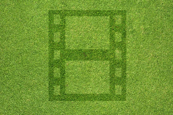 Ταινία εικονίδιο στο πράσινο γρασίδι υφή και φόντο — Φωτογραφία Αρχείου
