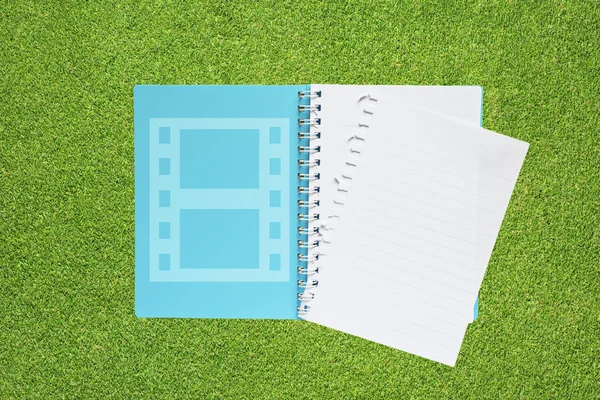Livro com ícone de filme no fundo da grama — Fotografia de Stock