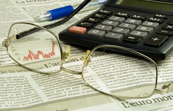 Gafas y calculadora en un periódico — Foto de Stock