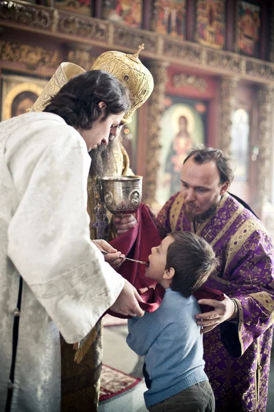 Évêque orthodoxe donne la communion à un petit garçon — Photo