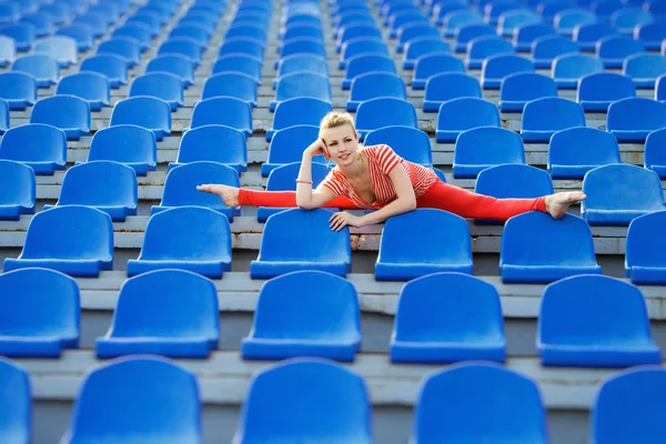 Спортивная женщина, раскладывающая сплиты на сиденьях стадиона — стоковое фото